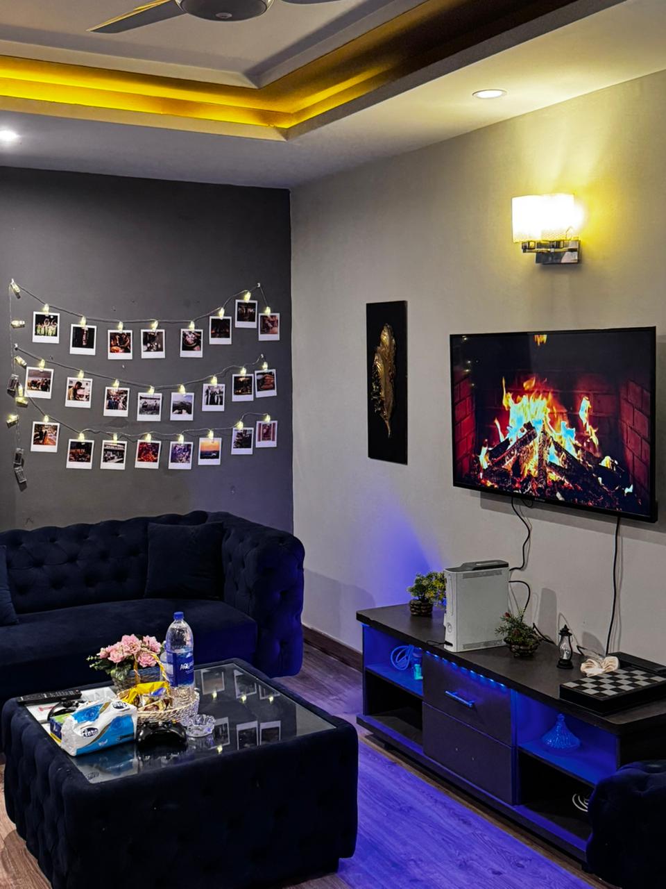 Living room with a navy velvet sofa and wall-mounted TV in the Aangan three-bedroom apartment in E-11, Islamabad
