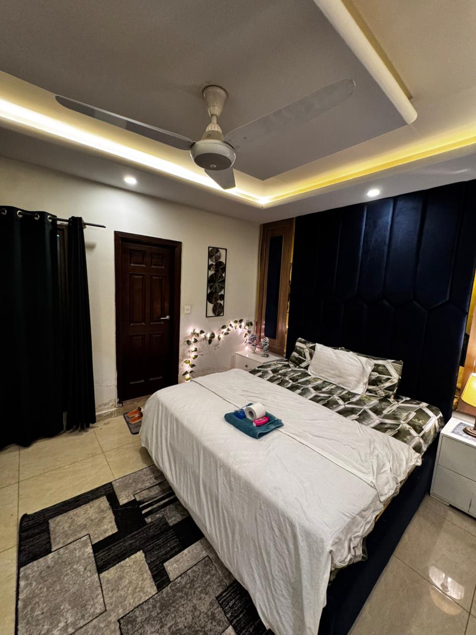 King bed and bedside table in the main bedroom of the Aangan three-bedroom apartment in E-11, Islamabad