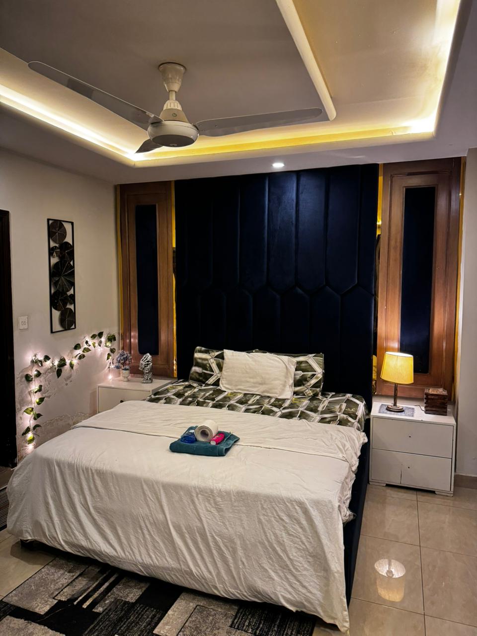 Main bedroom with a king bed and padded headboard in the Aangan three-bedroom apartment in E-11, Islamabad