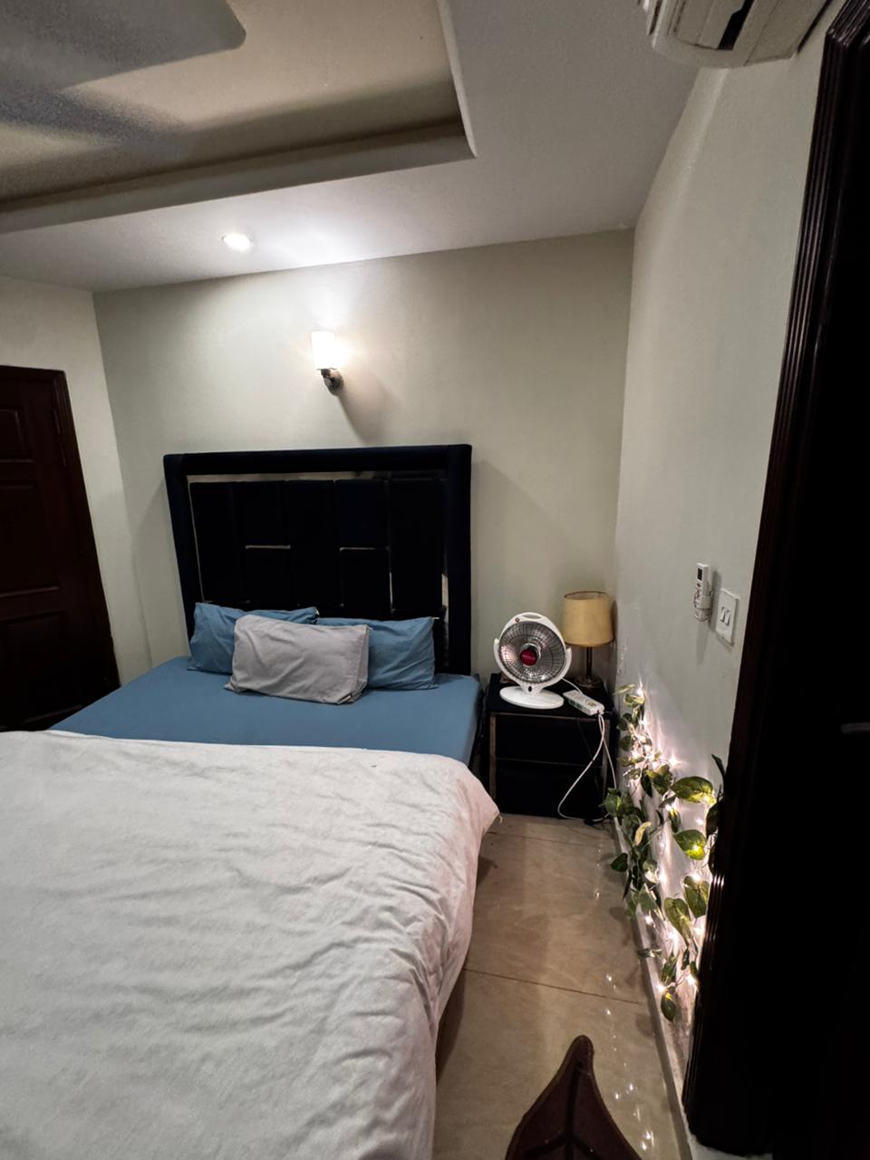 Bed with blue linen and a bedside table in a bedroom of the Aangan three-bedroom apartment in E-11, Islamabad