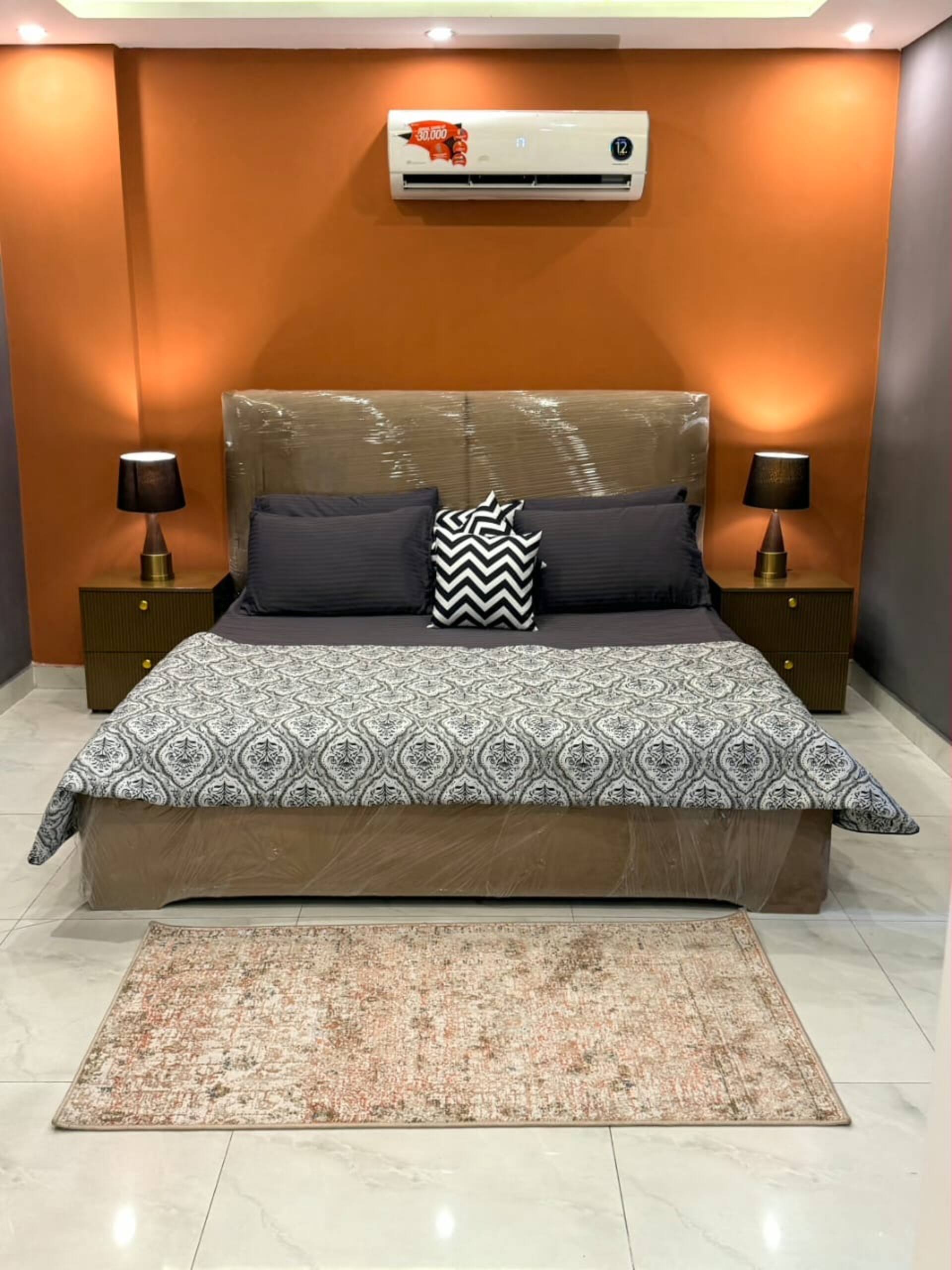 Bedroom lit by warm ambient LED lighting in The Amber Haven, the Aangan one-bedroom apartment facing Grand Jamia Mosque in Bahria Town Lahore