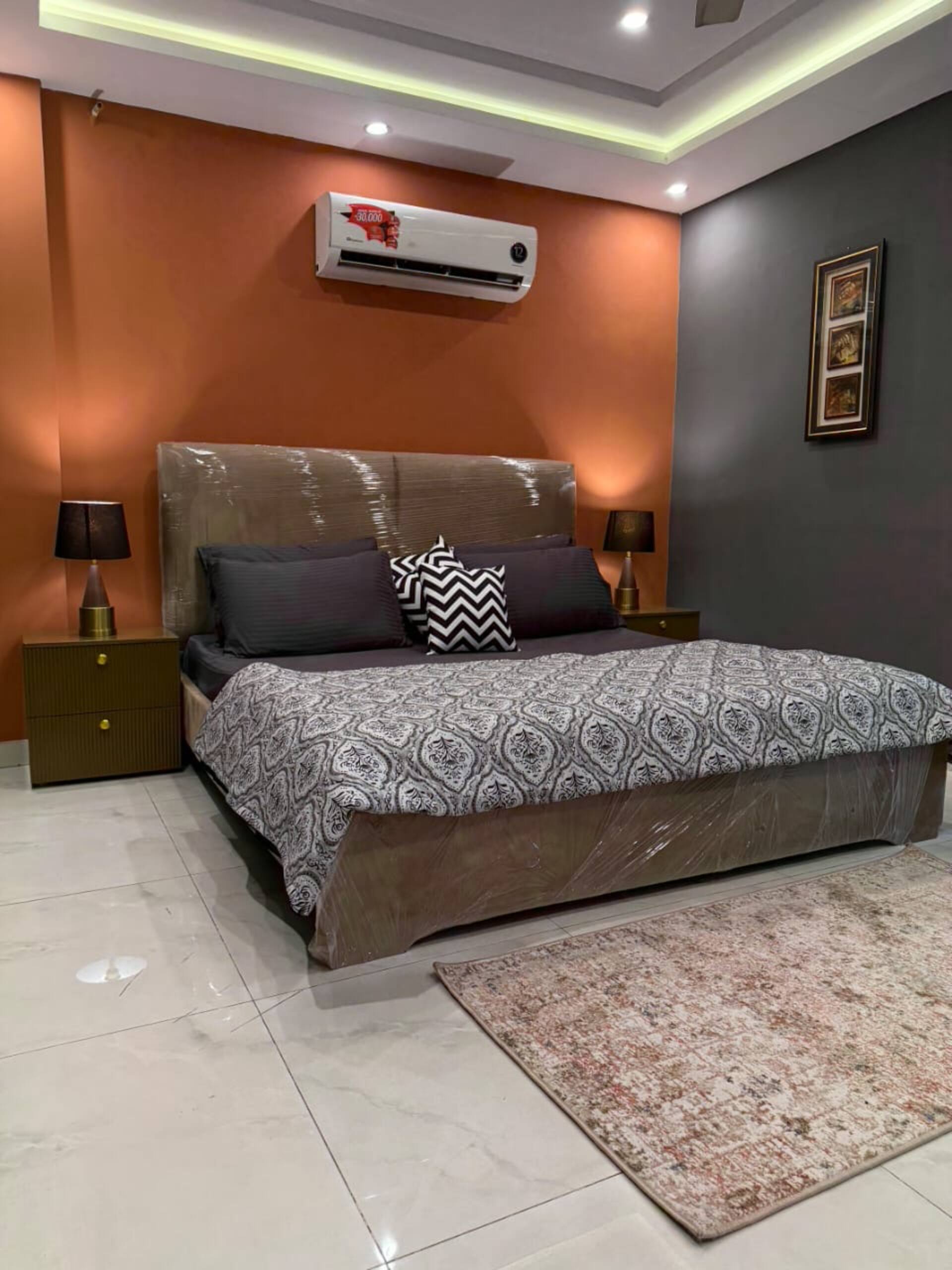 Bedroom seen from the side with bedside lamps and air conditioning in The Amber Haven, the Aangan one-bedroom apartment facing Grand Jamia Mosque in Bahria Town Lahore