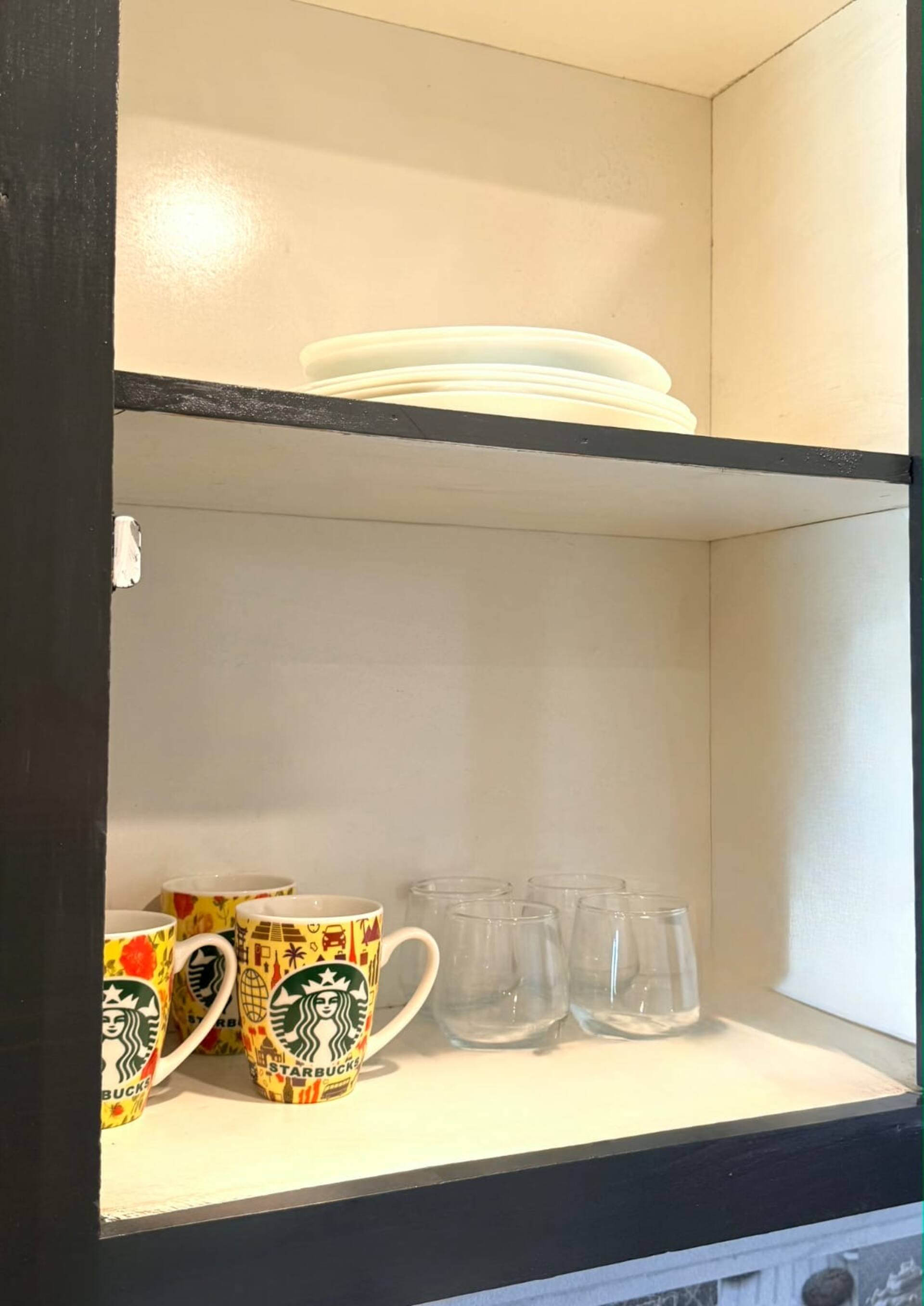 Mugs and glassware provided in the kitchenette of The Amber Haven, the Aangan one-bedroom apartment facing Grand Jamia Mosque in Bahria Town Lahore