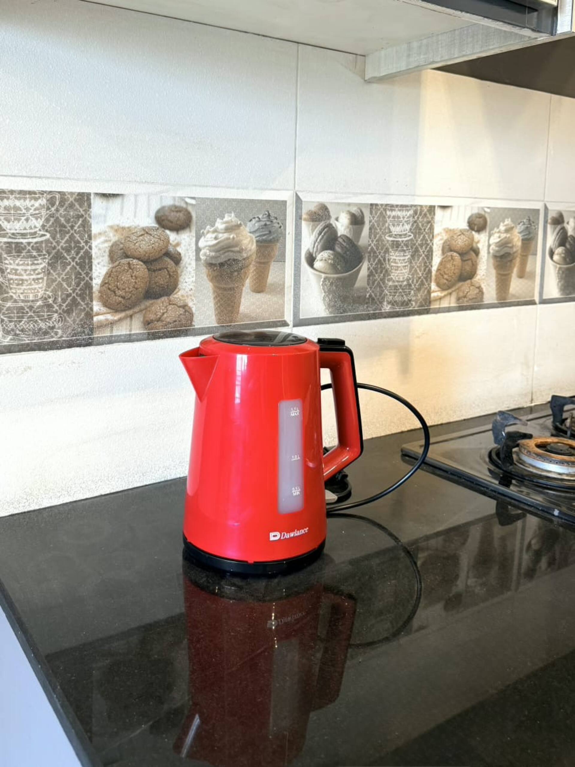 Kitchenette counter with an electric kettle and cooktop in The Amber Haven, the Aangan one-bedroom apartment facing Grand Jamia Mosque in Bahria Town Lahore