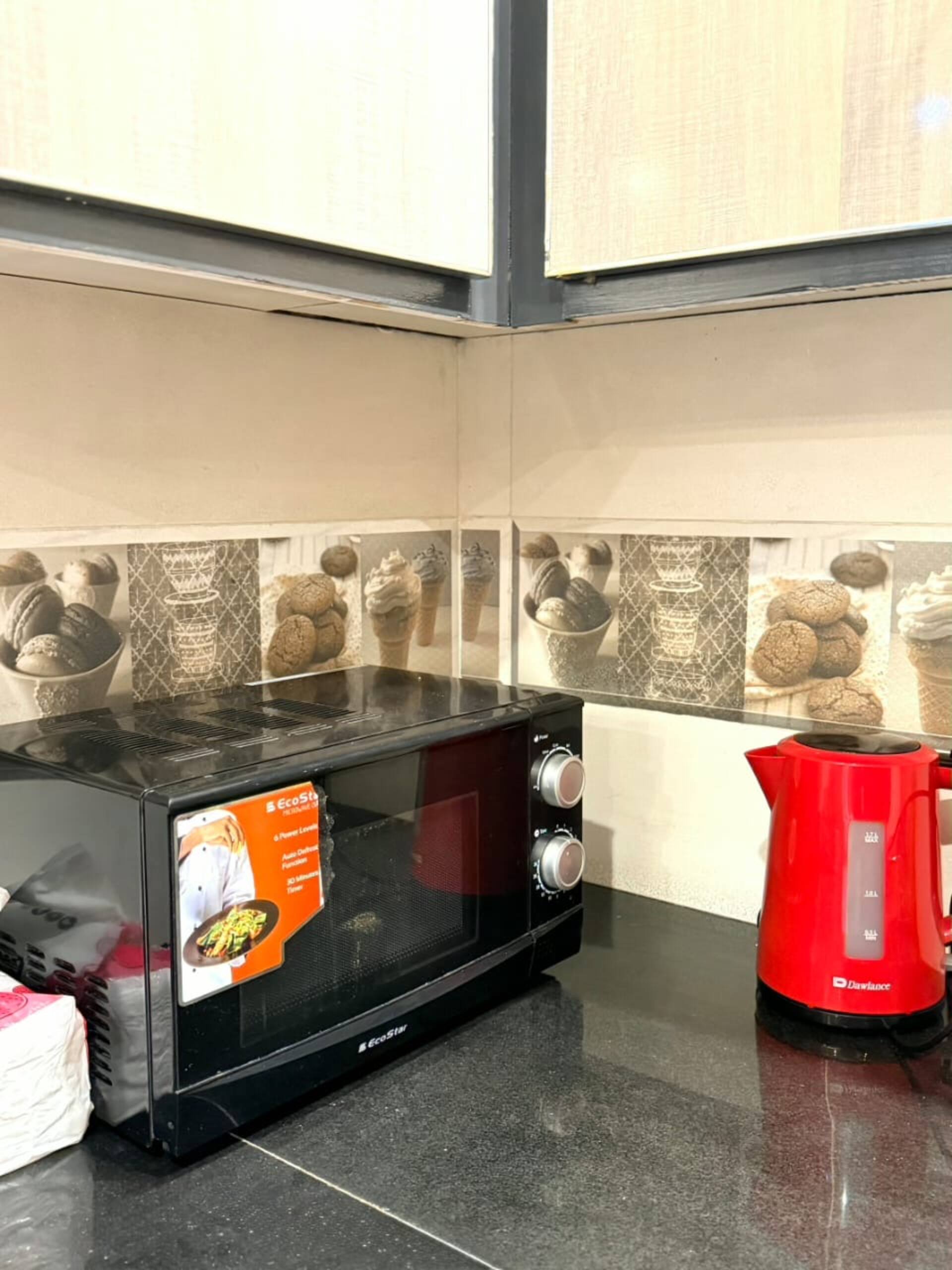 Microwave and kettle on the kitchenette counter of The Amber Haven, the Aangan one-bedroom apartment facing Grand Jamia Mosque in Bahria Town Lahore