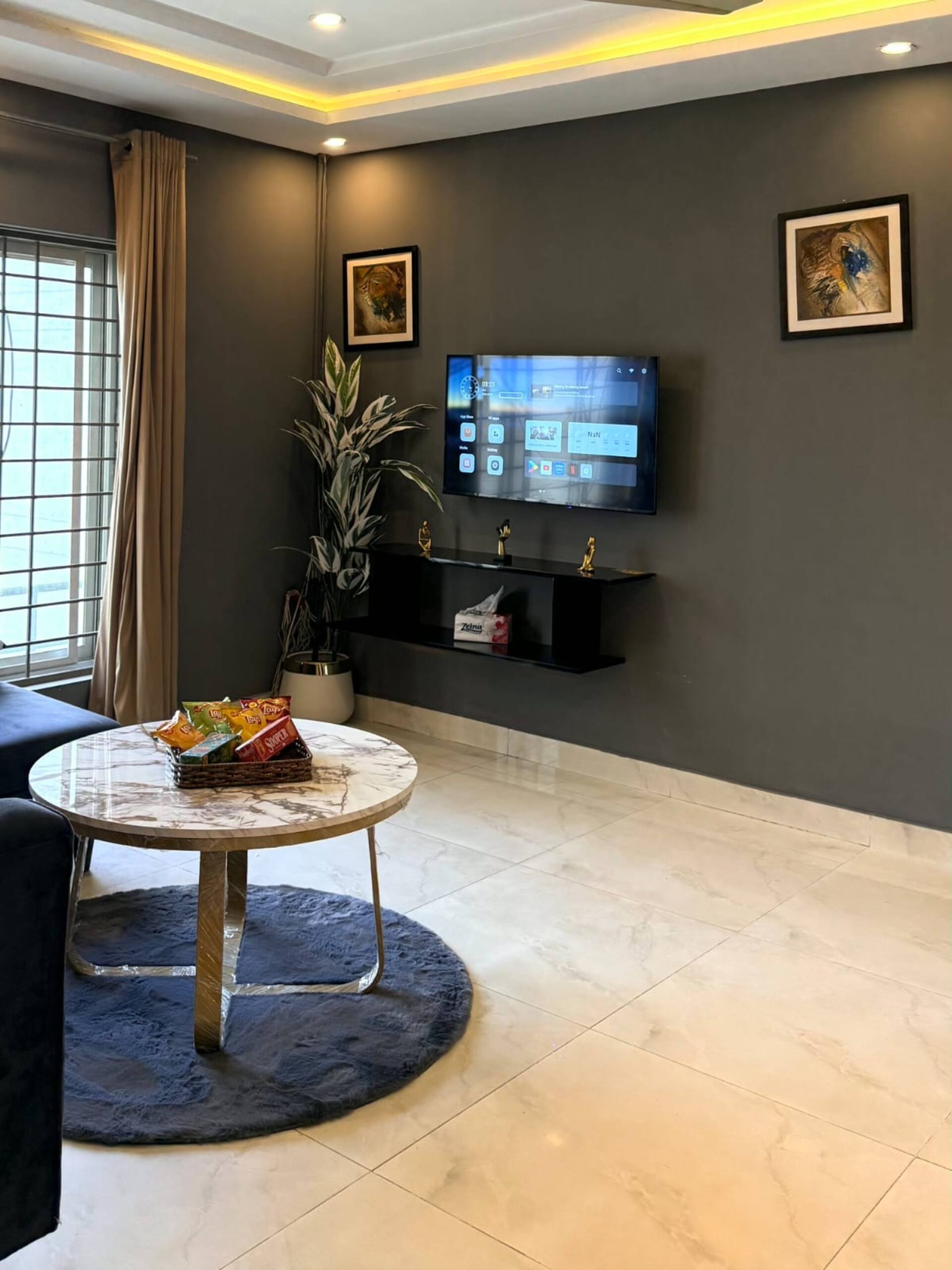 Living area with a wall-mounted smart TV and round table in The Amber Haven, the Aangan one-bedroom apartment facing Grand Jamia Mosque in Bahria Town Lahore