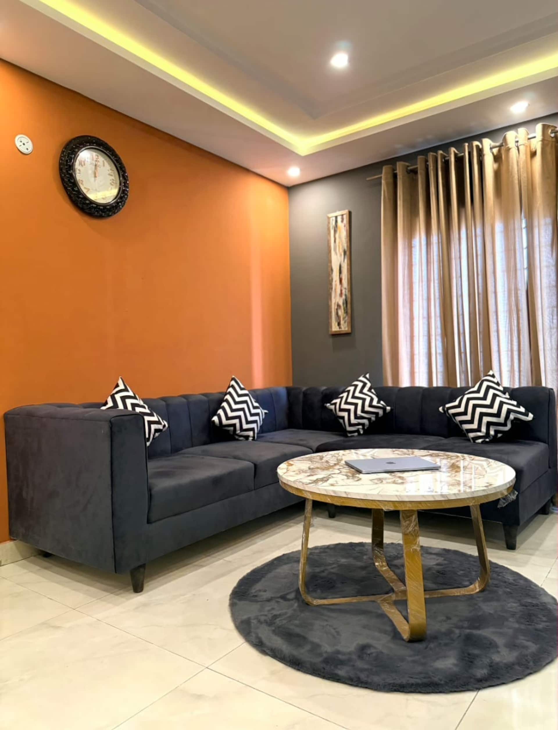 Living area with a sofa, coffee table and amber wall in The Amber Haven, the Aangan one-bedroom apartment facing Grand Jamia Mosque in Bahria Town Lahore