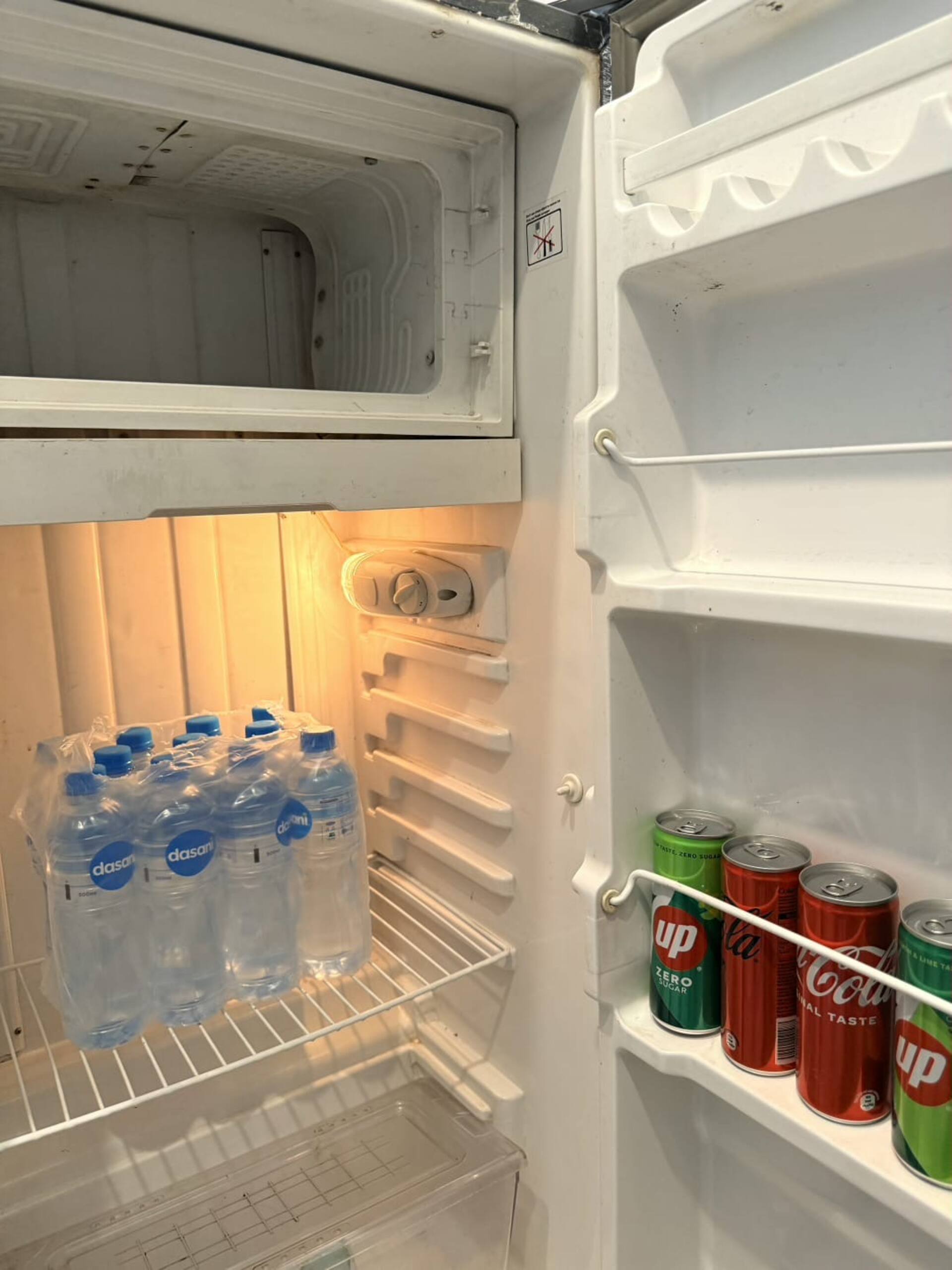 Refrigerator stocked with drinking water and drinks in The Amber Haven, the Aangan one-bedroom apartment facing Grand Jamia Mosque in Bahria Town Lahore