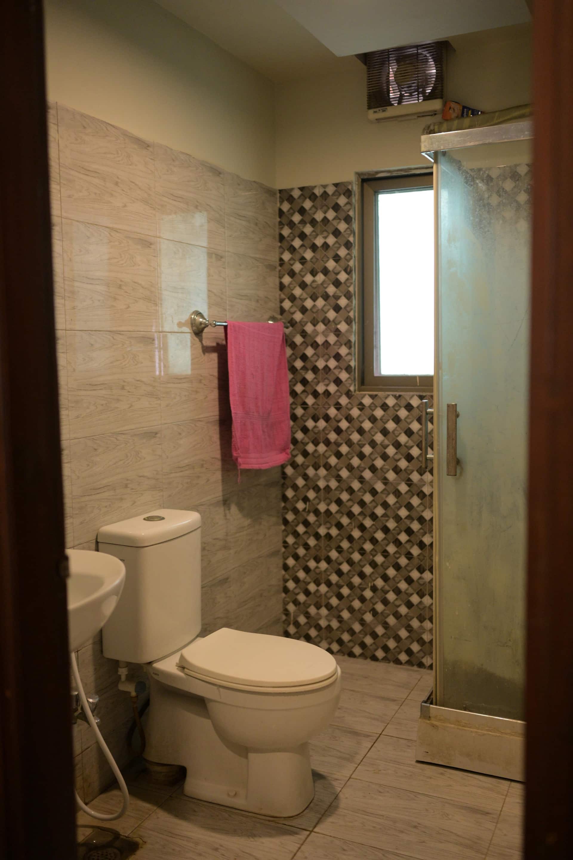 Second bathroom with a WC and tiled shower area in the Aangan three-bedroom gaming suite in Apollo Tower, E-11 Islamabad