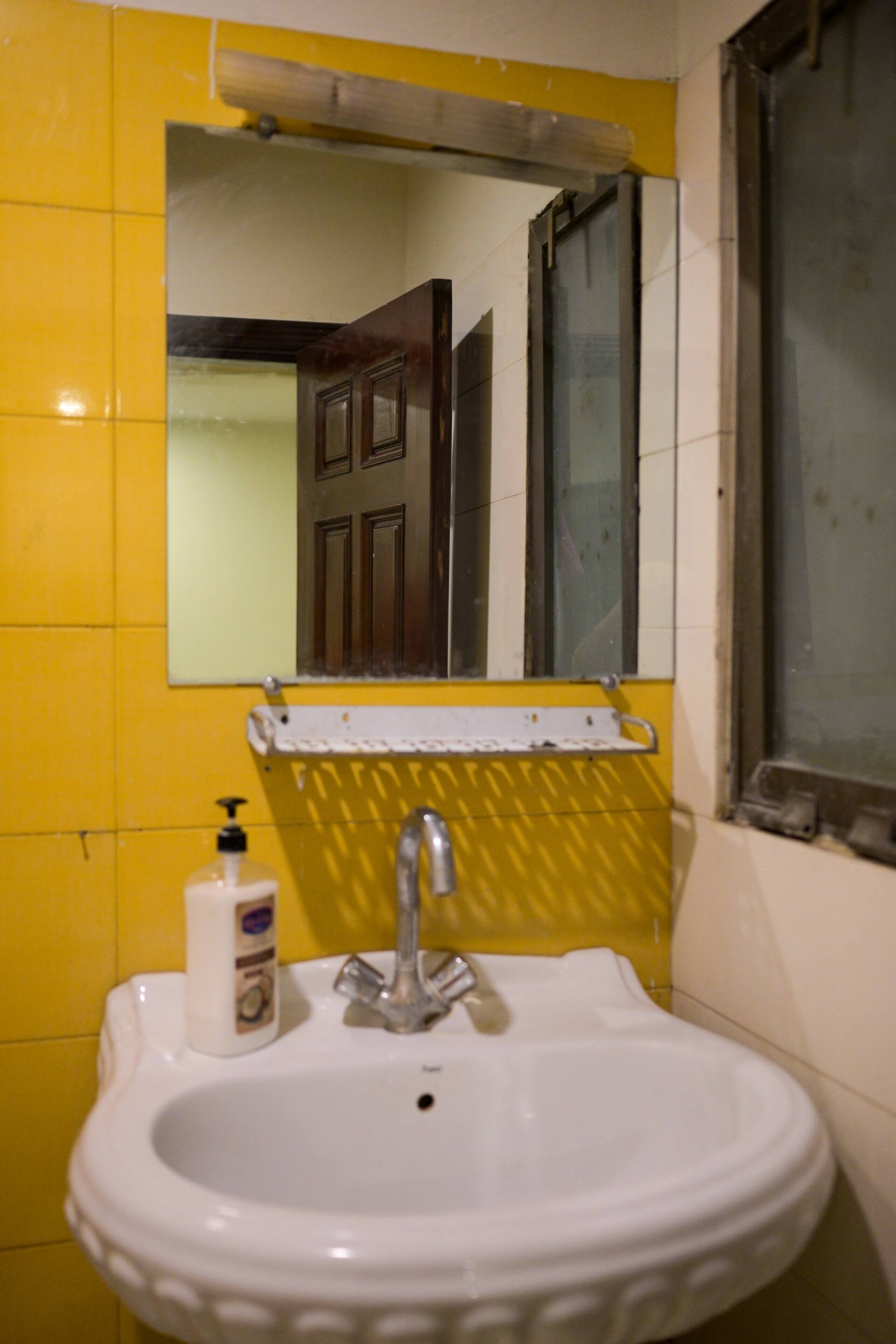 Third bathroom with a washbasin and mirror in the Aangan three-bedroom gaming suite in Apollo Tower, E-11 Islamabad
