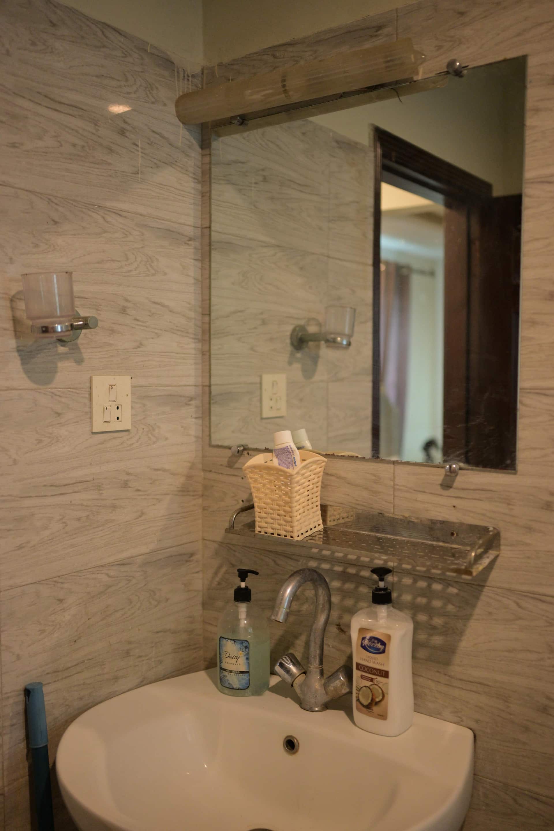 Bathroom vanity with a mirror and toiletries in the Aangan three-bedroom gaming suite in Apollo Tower, E-11 Islamabad