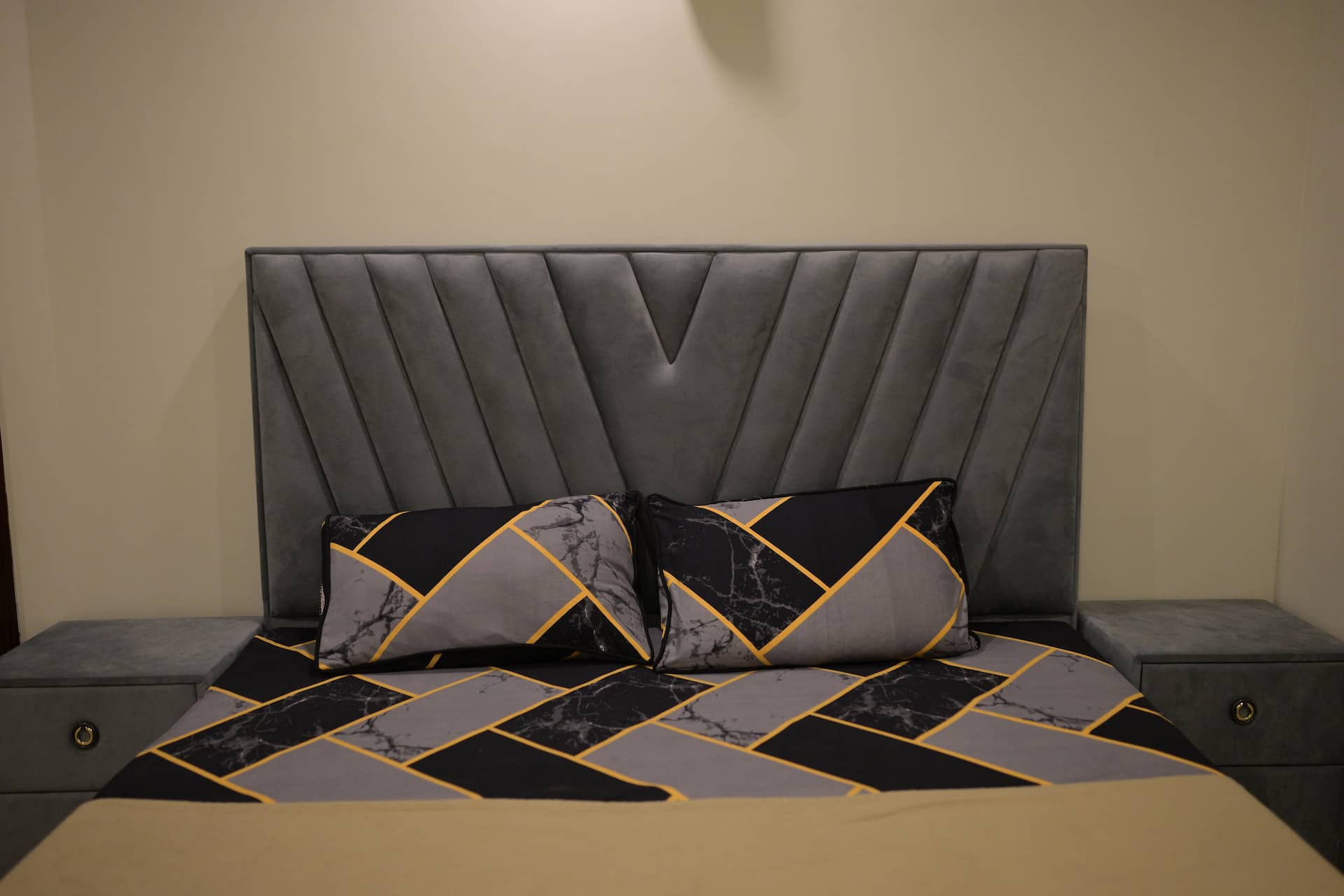 Close view of the bed linen and cushions on the grey headboard bed in the Aangan three-bedroom gaming suite in Apollo Tower, E-11 Islamabad