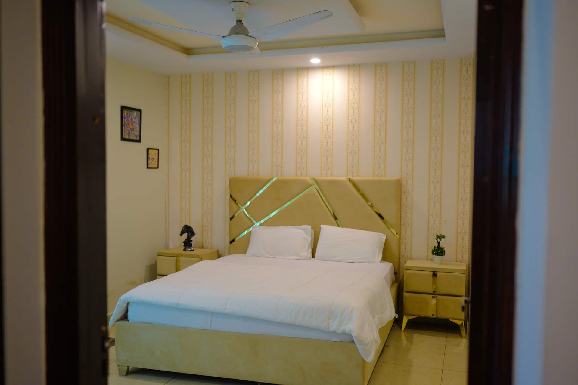 Bedroom with a double bed, cream headboard and bedside tables in the Aangan three-bedroom gaming suite in Apollo Tower, E-11 Islamabad