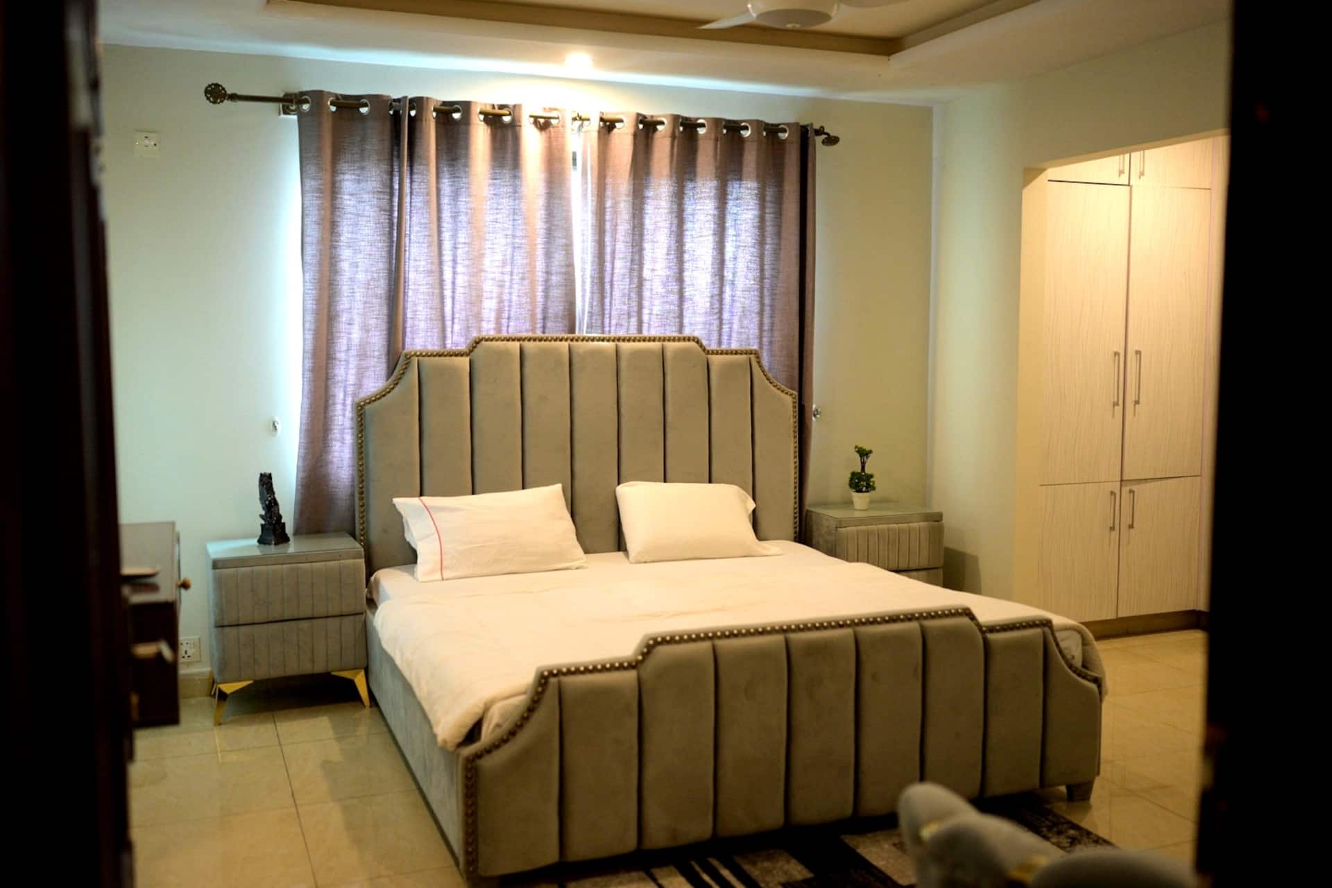 Second bedroom with a double bed, curtains and built-in wardrobe in the Aangan three-bedroom gaming suite in Apollo Tower, E-11 Islamabad