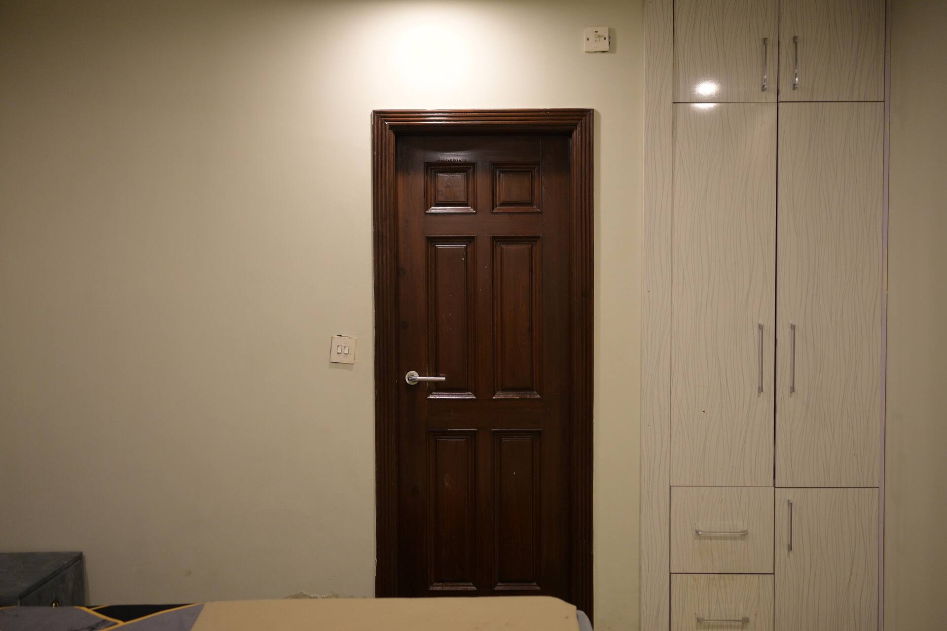 Bedroom door beside a full-height built-in wardrobe in the Aangan three-bedroom gaming suite in Apollo Tower, E-11 Islamabad