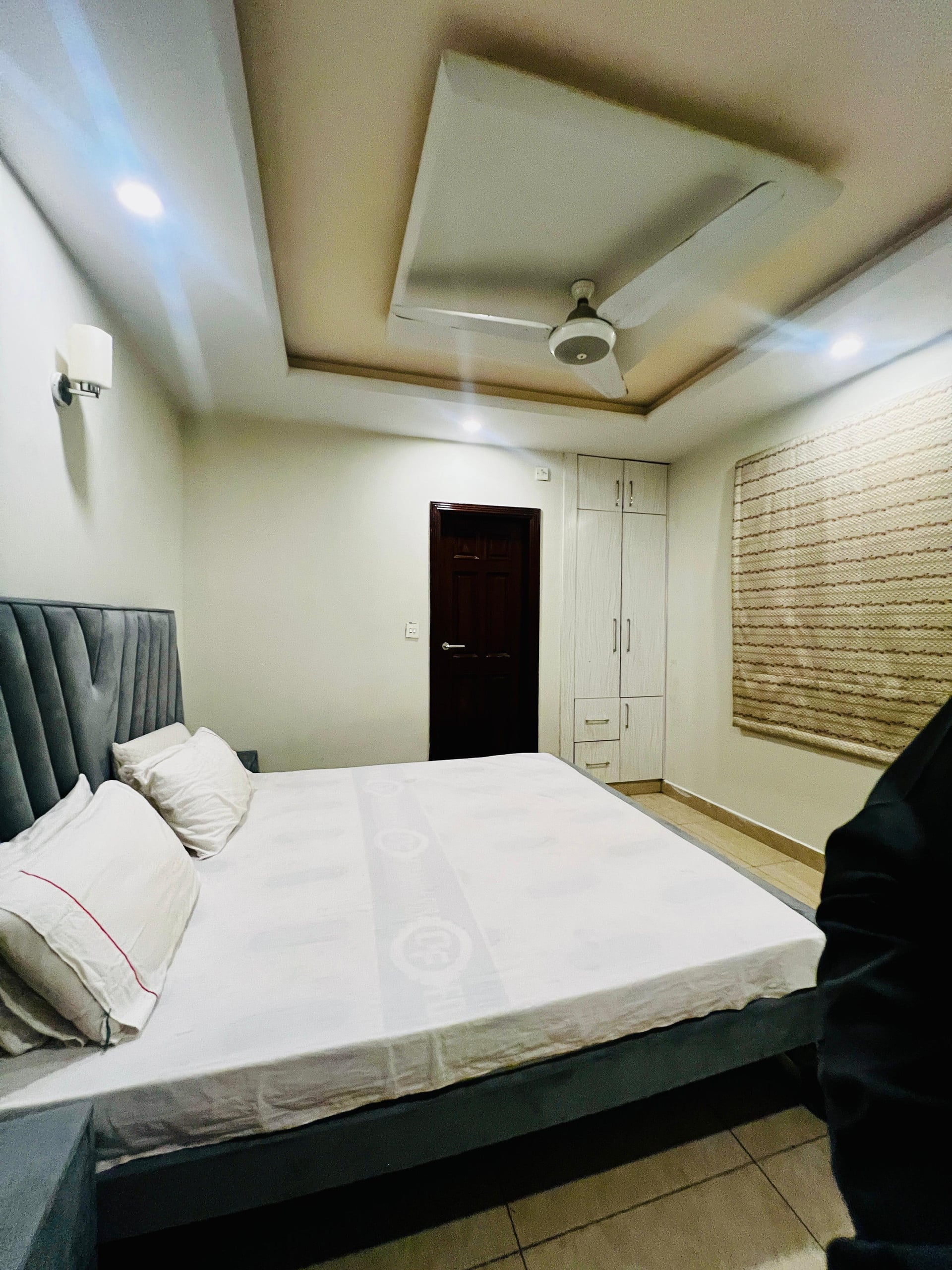Bedroom seen towards the door with a made-up double bed in the Aangan three-bedroom gaming suite in Apollo Tower, E-11 Islamabad