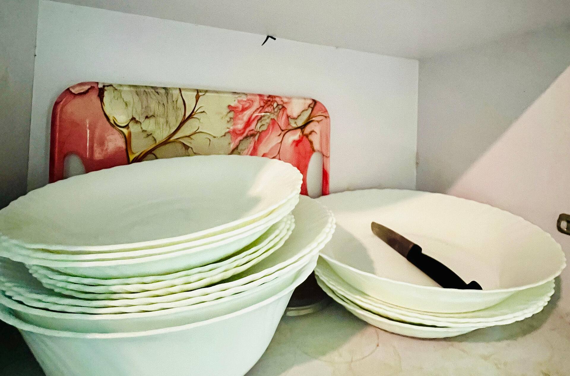 Stacked plates and serving bowls provided in the kitchen of the Aangan three-bedroom gaming suite in Apollo Tower, E-11 Islamabad