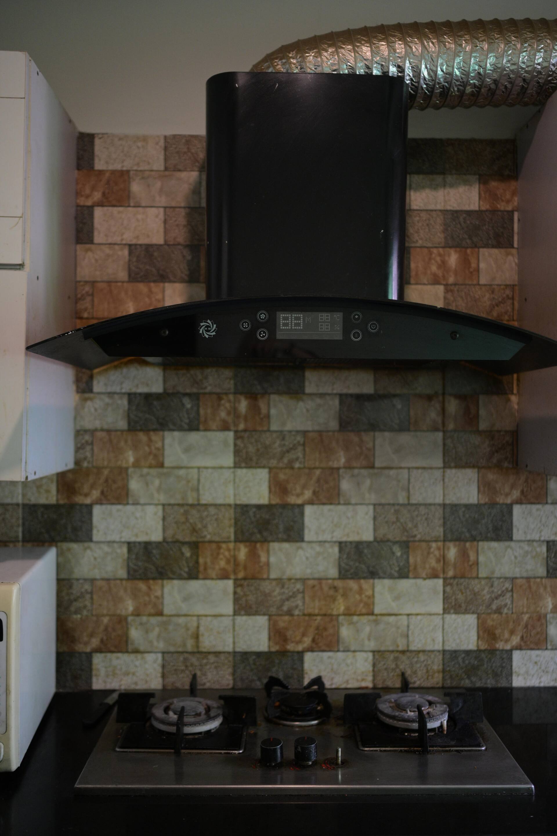 Gas cooktop with an extractor hood in the kitchen of the Aangan three-bedroom gaming suite in Apollo Tower, E-11 Islamabad