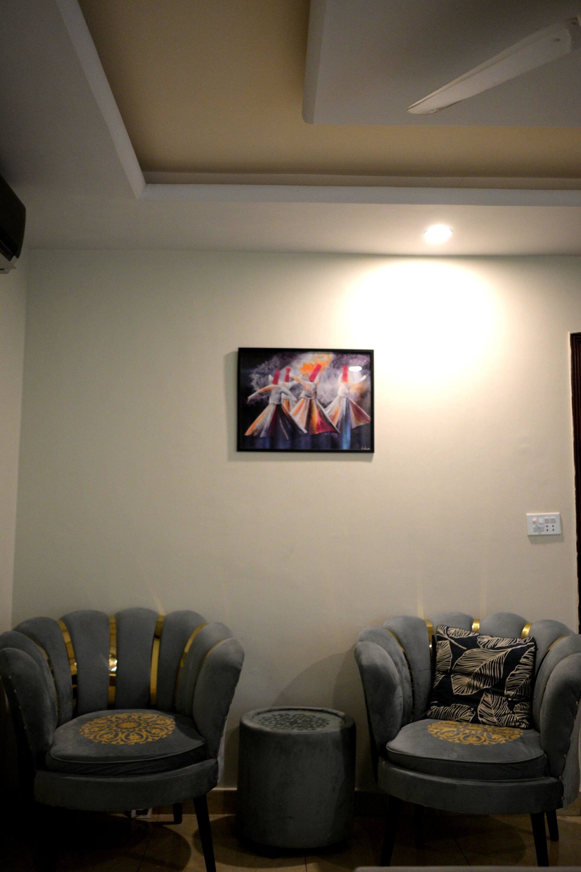 Two grey armchairs and a side table in the seating corner of the Aangan three-bedroom gaming suite in Apollo Tower, E-11 Islamabad