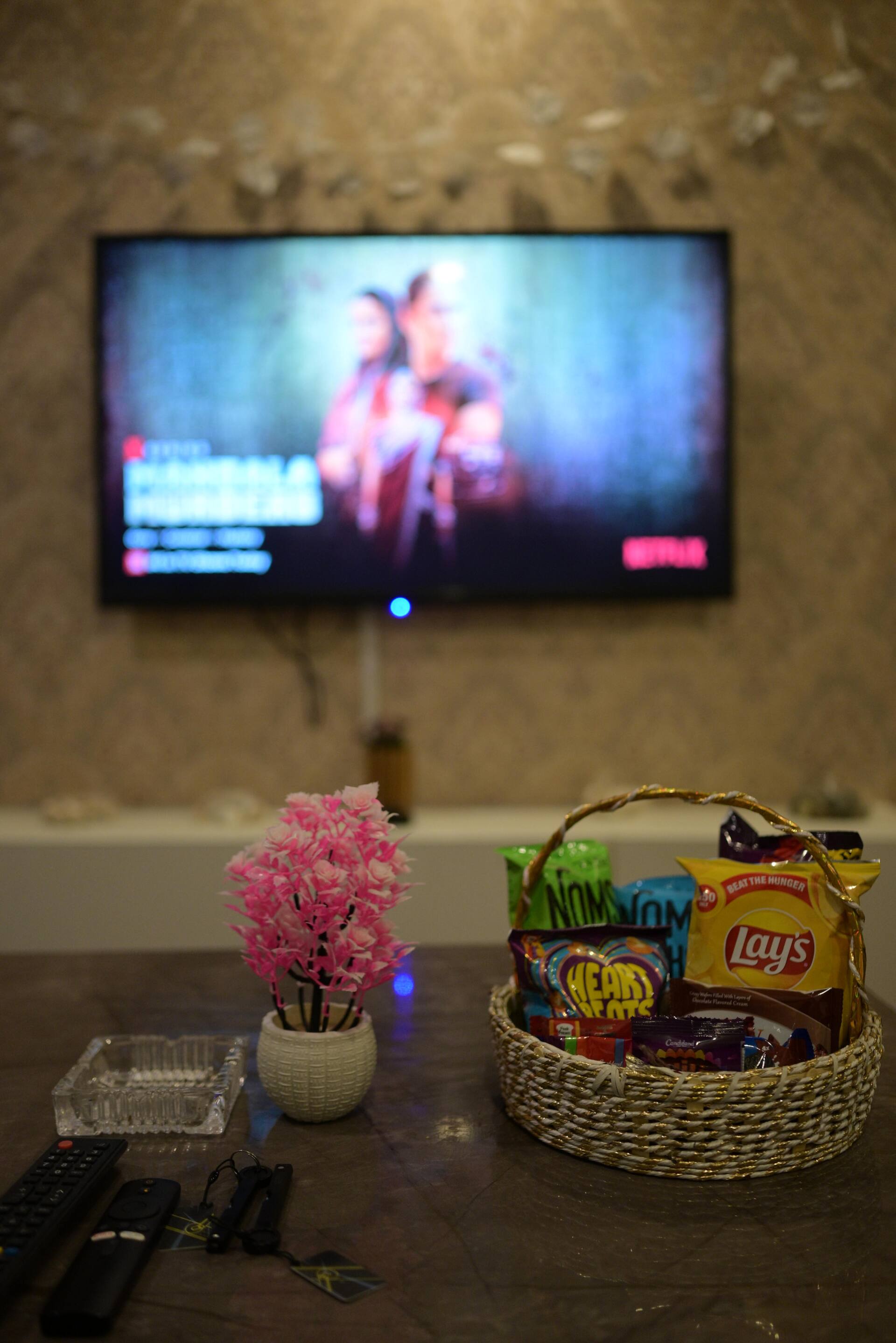 LED TV and a welcome snack basket on the console table in the Aangan three-bedroom gaming suite in Apollo Tower, E-11 Islamabad