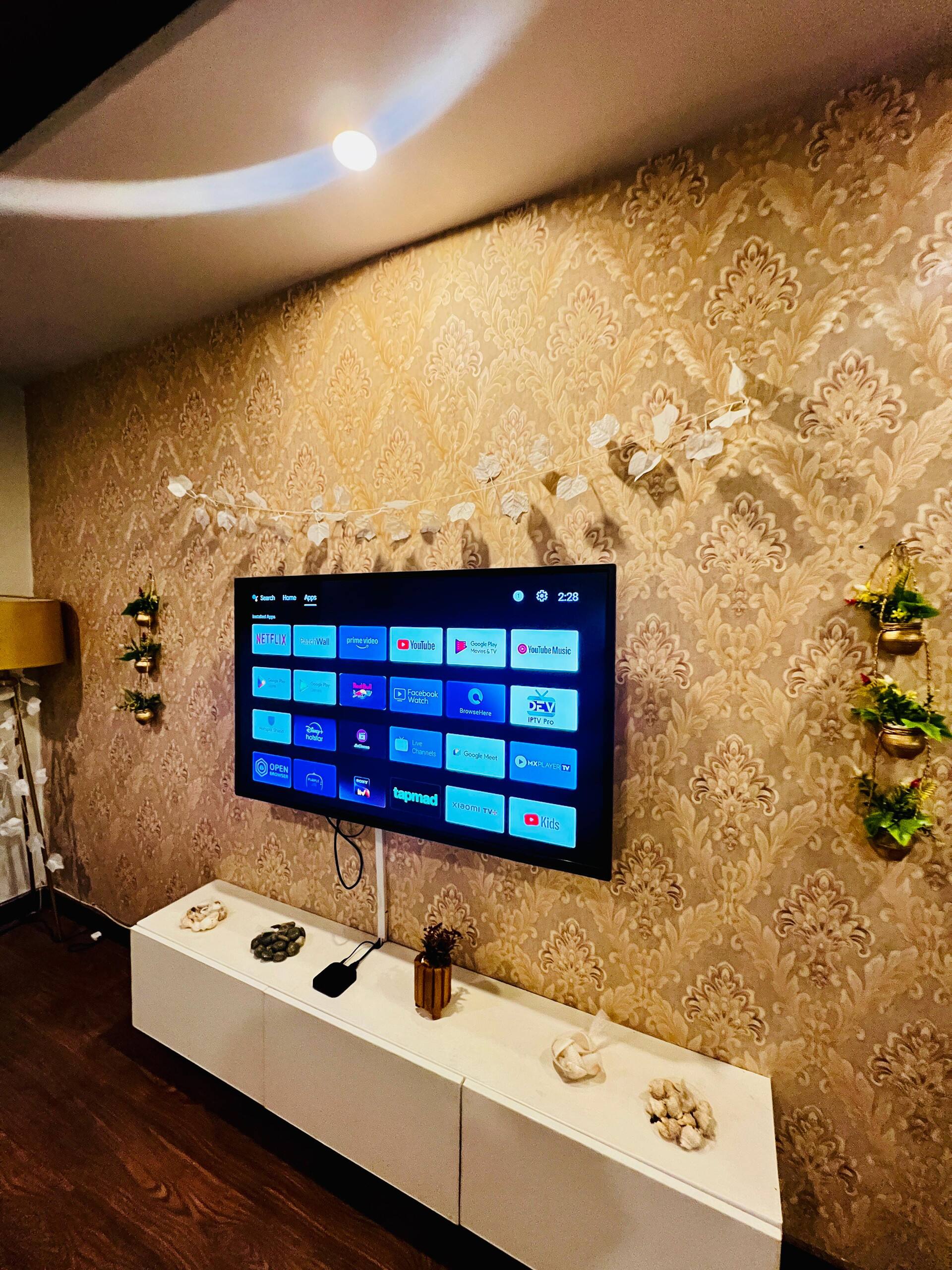 Wall-mounted LED TV above a media console in the lounge of the Aangan three-bedroom gaming suite in Apollo Tower, E-11 Islamabad