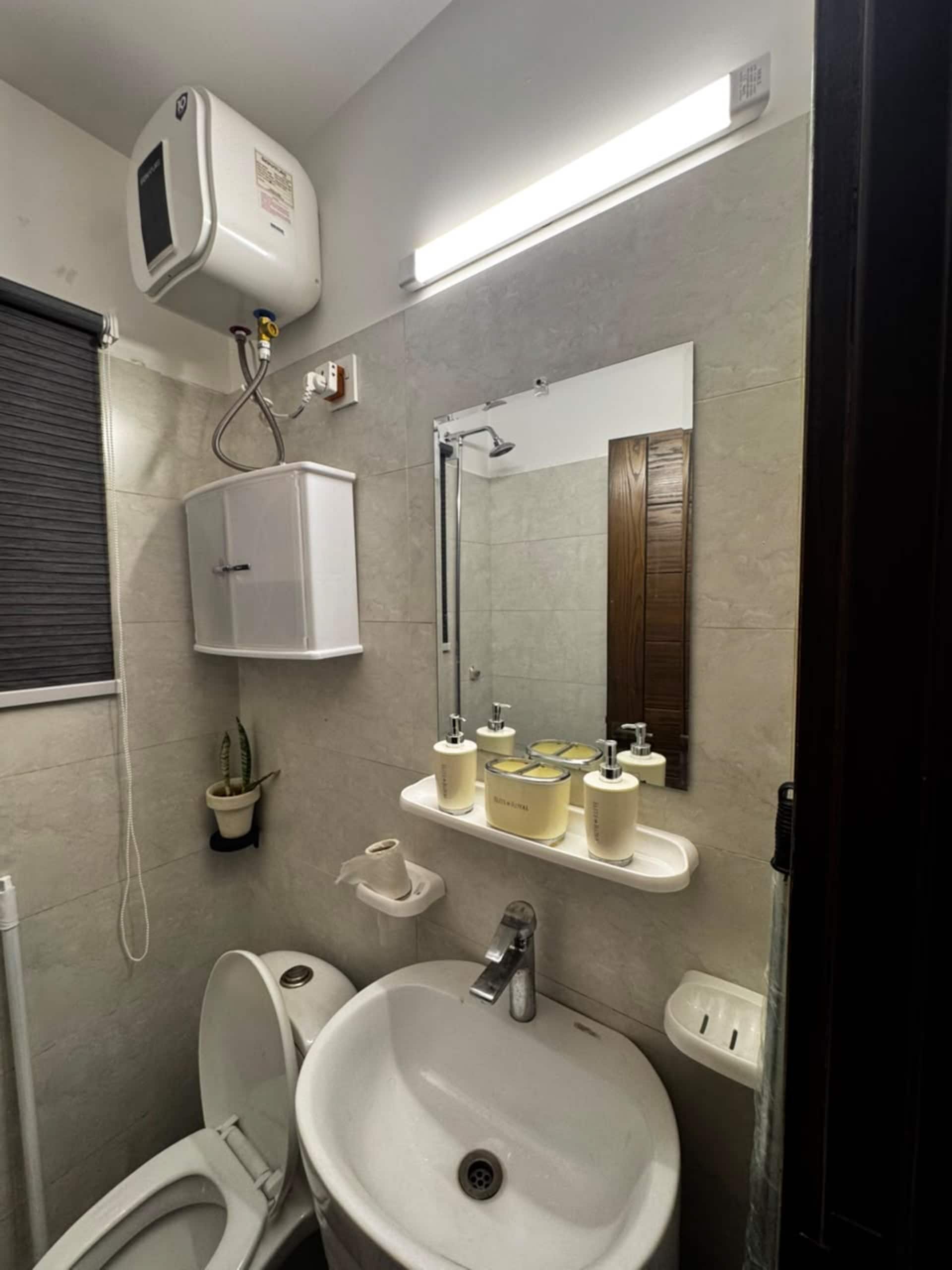 Bathroom with washbasin, mirror and water heater in the Aangan studio apartment near Islamabad International Airport
