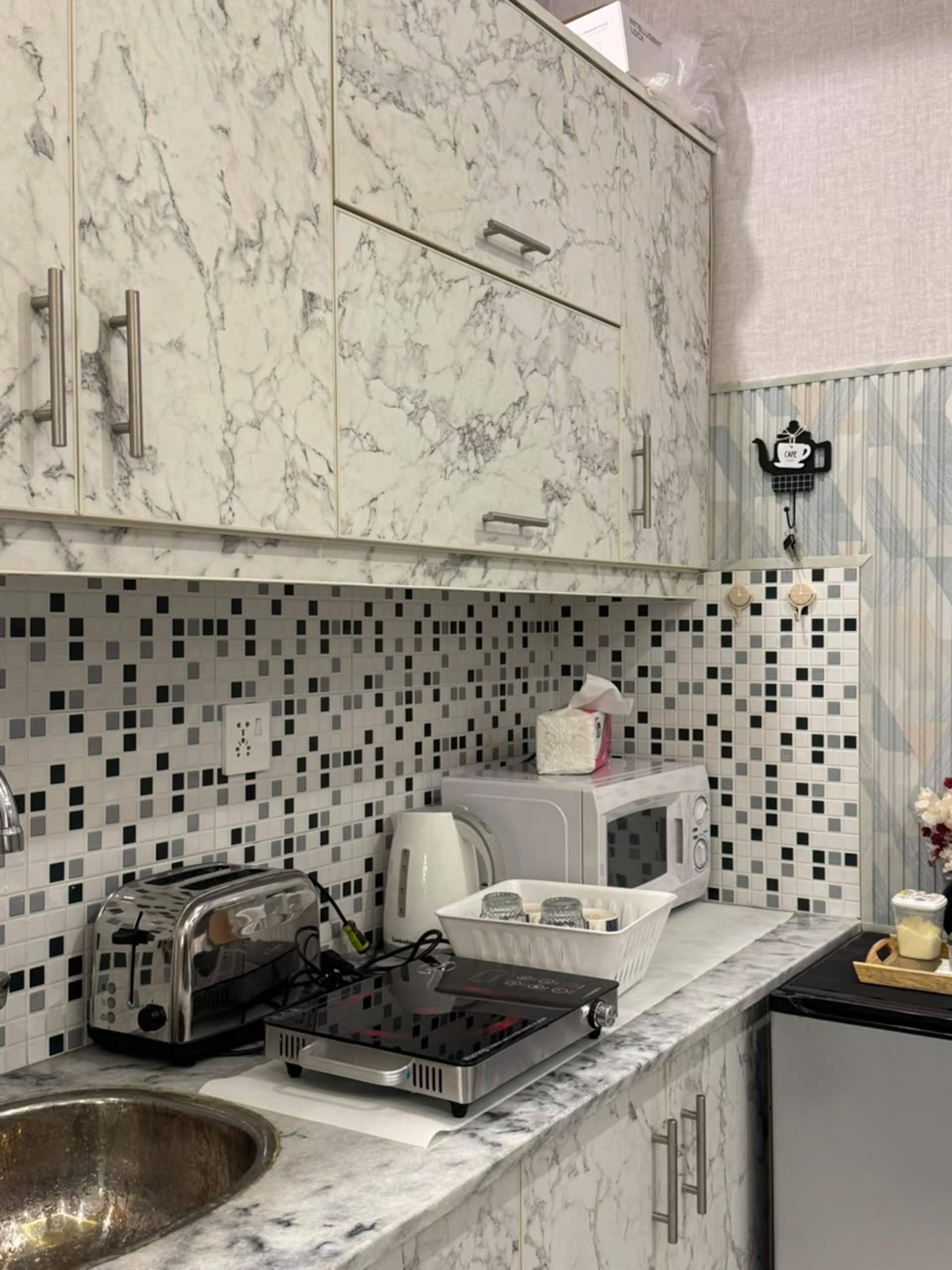 Kitchenette with sink, microwave, toaster and cabinets in the Aangan studio apartment near Islamabad International Airport