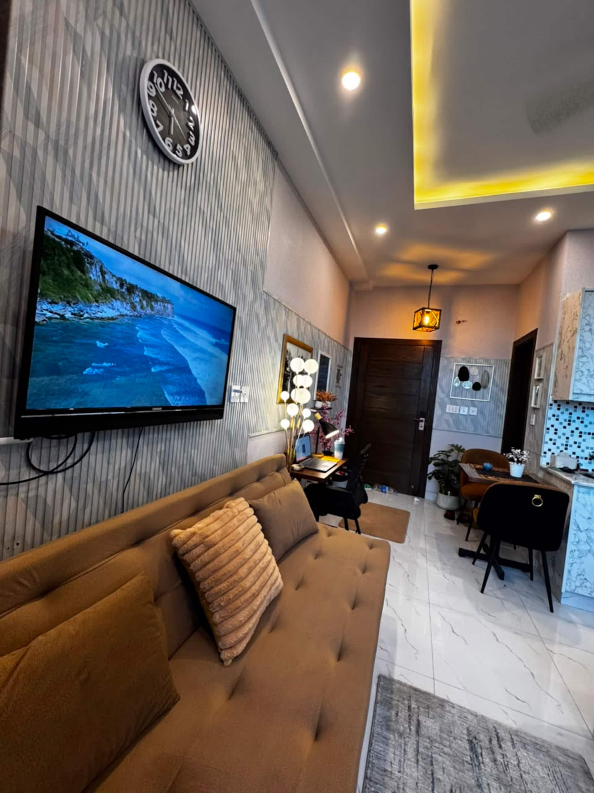 Sofa seating in front of the wall-mounted smart TV in the Aangan studio apartment near Islamabad International Airport