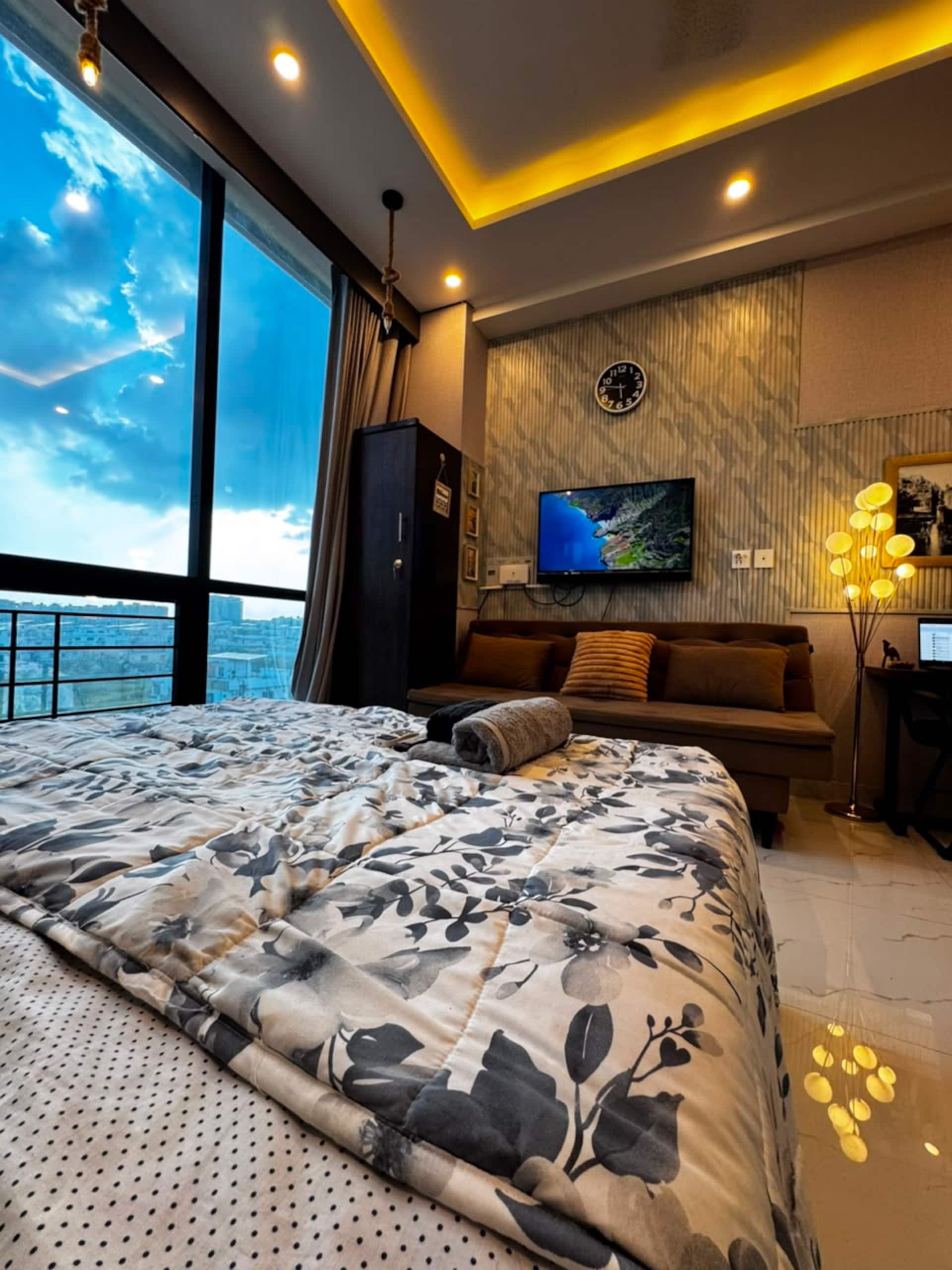 Daylight view across the bed, sofa and smart TV in the Aangan studio apartment near Islamabad International Airport