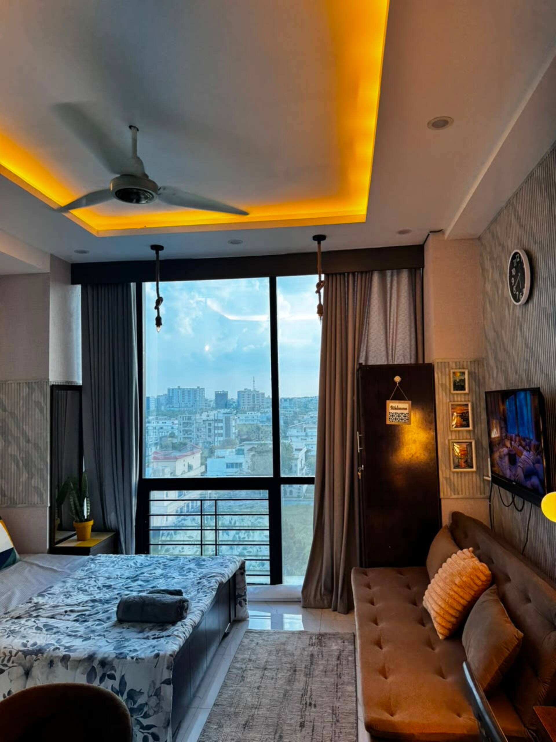 Queen bed and living area beside the window in the Aangan studio apartment near Islamabad International Airport
