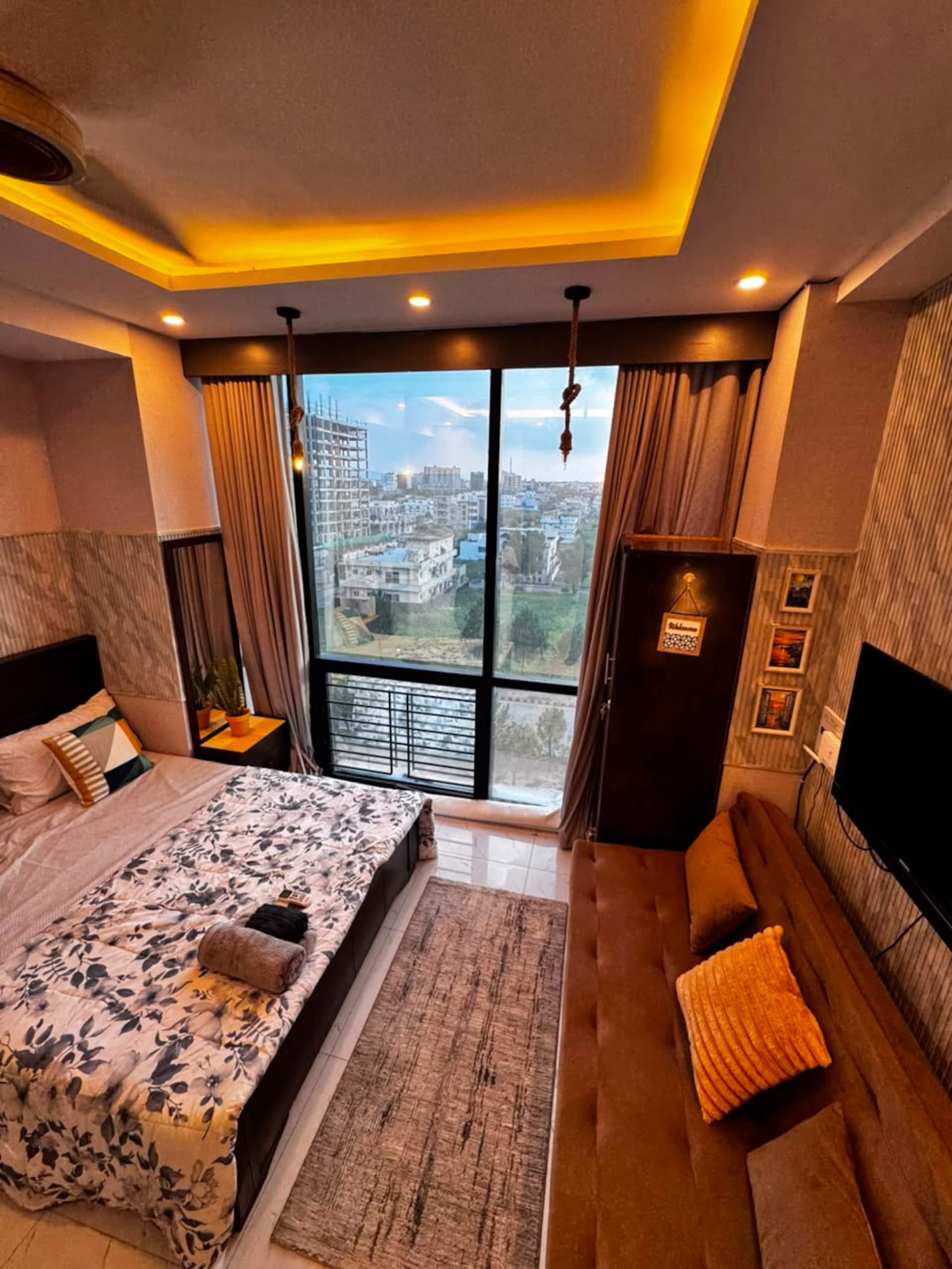 Studio apartment with a queen bed, sofa and floor-to-ceiling window in the Aangan studio apartment near Islamabad International Airport