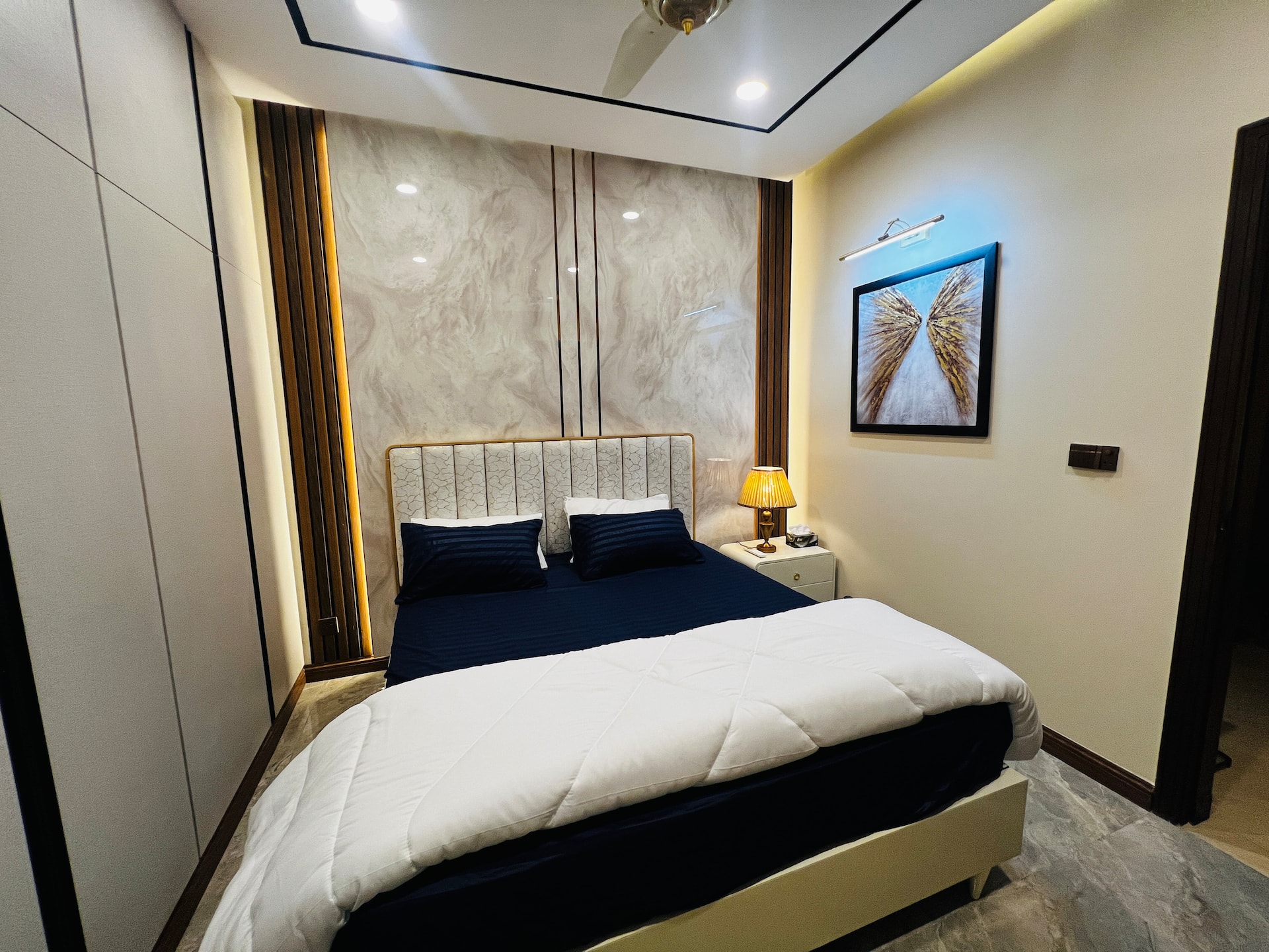 Bedroom with a king bed and upholstered headboard in the 3-bedroom Aangan apartment in Zeta Mall, Islamabad