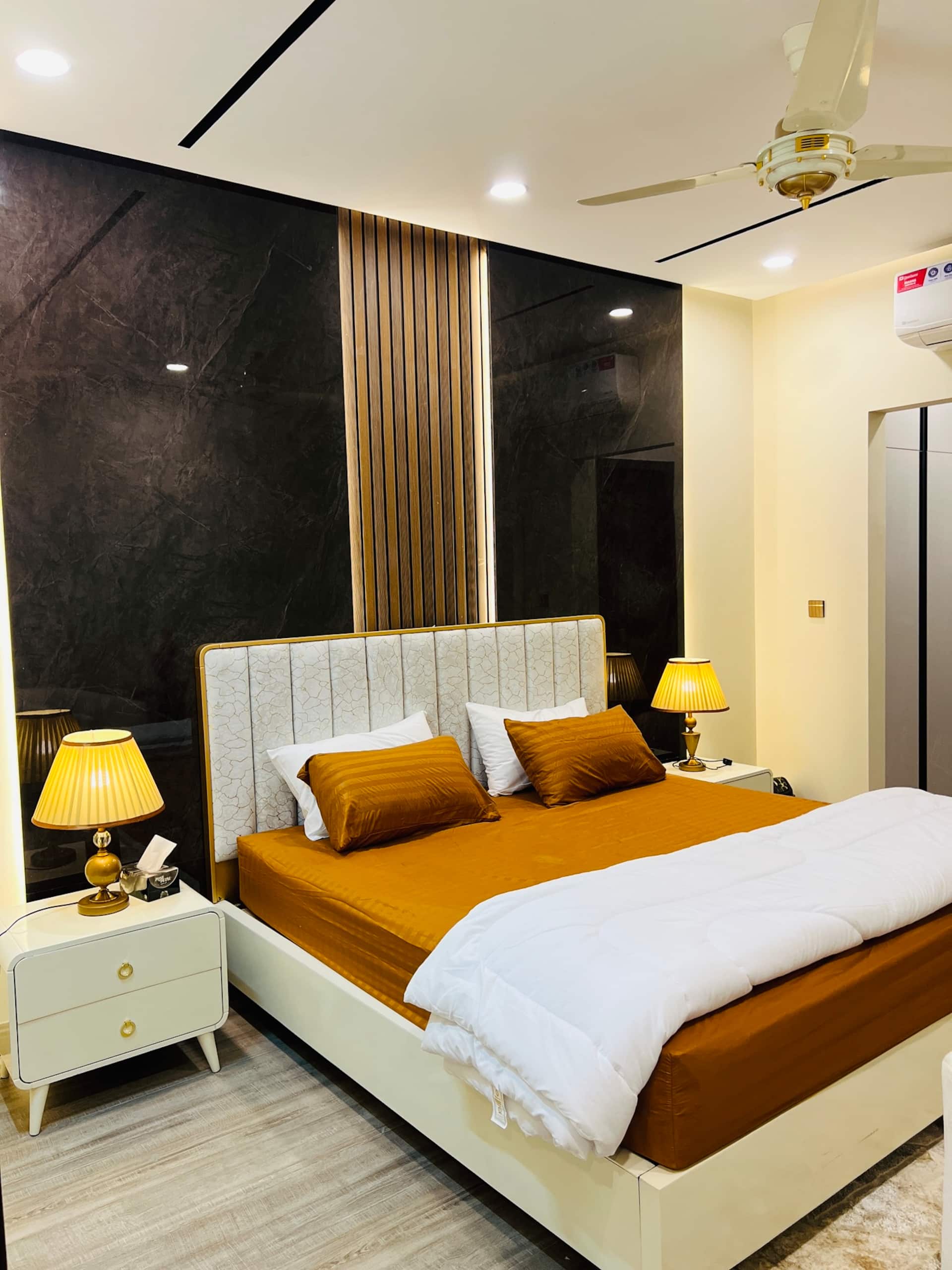 Second bedroom with a king bed and bedside lamps in the 3-bedroom Aangan apartment in Zeta Mall, Islamabad