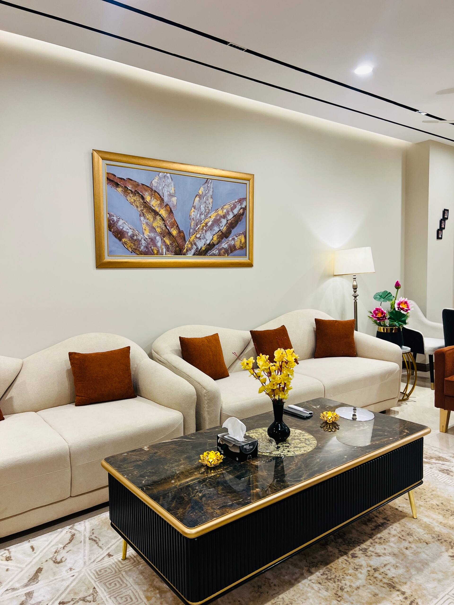 Seating area with cream sofa and armchairs in the living room of the 3-bedroom Aangan apartment in Zeta Mall, Islamabad