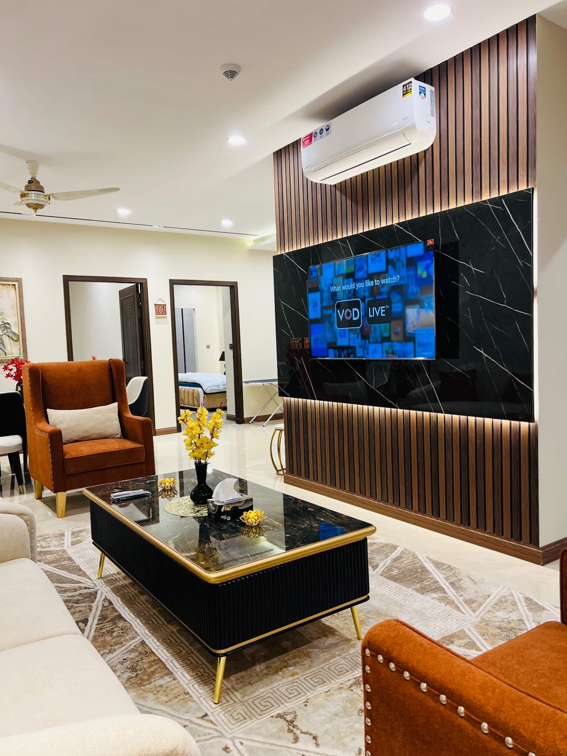 Living room with a wall-mounted smart TV and air conditioning in the 3-bedroom Aangan apartment in Zeta Mall, Islamabad